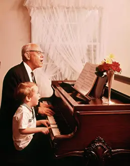 Oldtime Prints: 1970s ELDERLY GRANDFATHER AND YOUNG GRANDSON SINGING AND PLAYING A GRAND PIANO TOGETHER