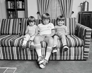 Oldtime Prints: 1970s THREE SIBLINGS SITTING ON COUCH LOOKING AT CAMERA