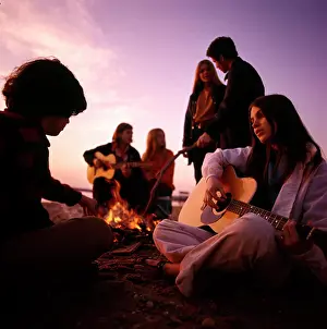 Sound Prints: 1970S Teenagers Gathered Around Beach Campfire Playing Acoustic Guitars