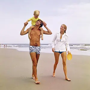 Mid Adultman Prints: 1970s YOUNG FAMILY WALKING DOWN BEACH TODDLER RIDING ON FATHERS SHOULDERS
