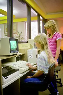 Students Prints: 1980s 2 GIRLS WORKING ON COMPUTER IN PUBLIC LIBRARY COMPUTER LAB PAY AS YOU GO VENDING DEVICE