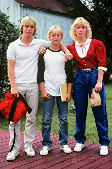 Denim Prints: 1980s THREE BLOND TEENAGERS BROTHERS SISTERS STANDING TOGETHER LOOKING AT CAMERA ON FIRST DAY OF SCHOOL