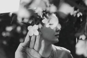 Abstract contemporary art collage black and white portrait of young woman with flowers on face hides her eyes