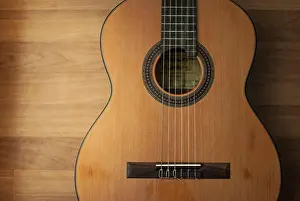 Audio Prints: Acoustic guitar resting against a wooden background