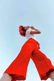 Individualism Prints: Active young urban woman with highlighted hair standing against sky