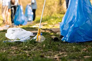 Activist Prints: Activist using claw tool to collect rubbish and plastic junk from the ground