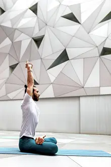 Wellness Gallery Prints: Adult bearded man in sportswear sitting crossed legged and meditating with closed eyes