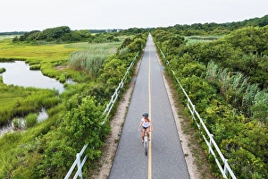 Biking Prints: Aerial drone of Woman biking through Cape Cod Marshes bike path