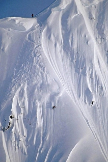 Difficult Prints: Aerial of extreme skiers skiing down steep mountain slope heli_skiing Chugach Mtns Southcentral Alaska