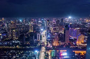 Drone View Prints: Aerial night cityscape of skyscrapers and multi lane highway traffic in modern city center of Jakarta