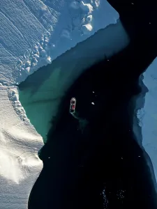 Glacial Prints: Aerial top-down drone view a red boat driving between icebergs