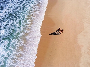 Snorkeling Prints: Aerial view of a couple carrying snorkeling gear walking on the beach