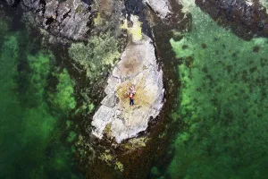 1 2 Years Old Prints: Aerial view of family lying on rock surrounded by clear green water