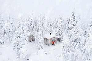 Finland Prints: Aerial view of happy couple enjoying the winter holidays in a frozen hut in the snowy forest