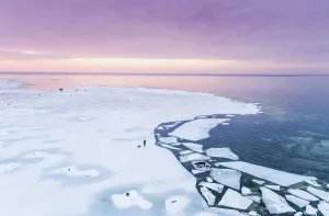 Aerial Prints: Aerial view of a man walking his dog on the frozen sea in Muraste at sunset, Estonia