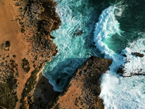 Foam Prints: Aerial top view of sea waves hitting rocks on the beach with turquoise