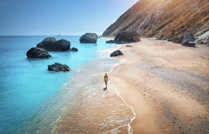 Adriatic Prints: Aerial view of walking young woman on empty sandy beach near sea with waves at sunset