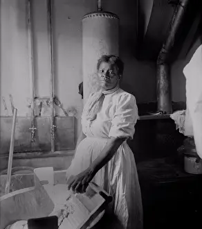 African American woman standing by a washtub with her hand on a washboard. Ca. 1920