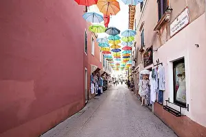 Urban Environment Prints: Alley with colourful umbrellas suspended over a street, Novigrad, Istria, Croatia, Europe