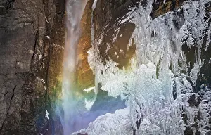 Weather Prints: Amazing scenery with rainbow at small waterfall falling from sheer cliff and frozen rocky wall in Canadian countryside