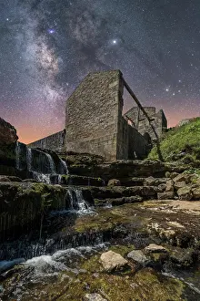Calm Prints: From below of ancient stone castle and small waterfall on stairs under dark sky with stars and milky way