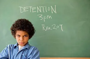 Student Prints: Angry mixed race boy frowning in classroom detention