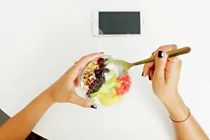 Anonymous Prints: From above anonymous female enjoying healthy dish with fruits and walnuts over table with smartphone in restaurant