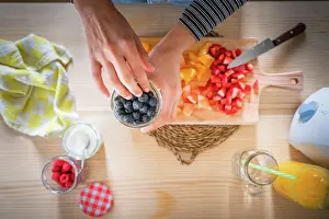 Anonymous Prints: Anonymous woman taking blueberries from jar while cooking healthy vitamin food from fresh fruits at home