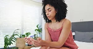 Decision Prints: Anxiety, woman and stress with pregnancy test on bed for fertility
