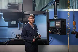 Manual Worker Prints: Apprentice holding a u-bolt strap in front of CNC machine