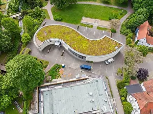 Contemporary Prints: Architecturally curved building with green roof and vehicles in the car park