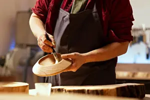 Expert Prints: Artisan applying paint on wood object using paintbrush after sanding surface to ensure smoothness