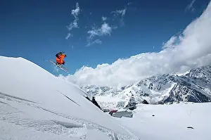 Mountain Chain Prints: Athlete skier freestyle jumping in orange ski suit in snowy mountains on a sunny day