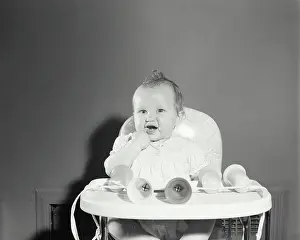 Baby Clothing Prints: Baby girl sitting in a high chair with her finger in her mouth