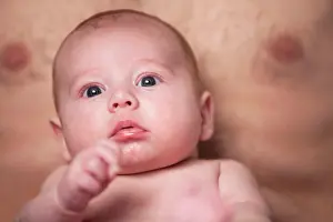 Breast Prints: Baby is looking up on daddys lap Little baby boy is having a relaxing time on his white blanket