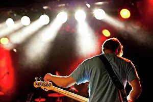Luminous Prints: Bass player tuning his bass on stage