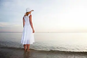 Schoen Prints: On the beach Woman in hat and white dress on the beach