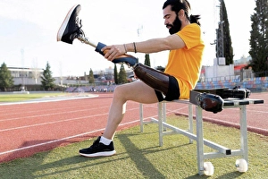 Handicapped Prints: Bearded man removing prosthetic leg sitting on bench