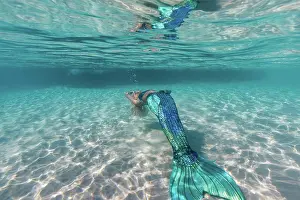 Attractive Prints: Beautiful carefree young mermaid with blue fishtail swimming underwater in deep bright sea