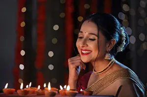 Occasion Prints: Beautiful Indian woman enjoying and smiling at home on the occasion of Diwali