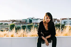 Leather Prints: Beautiful stylish woman in black outfit sitting with city landscape in Lisbon on sunny day