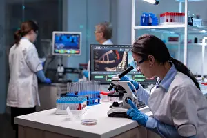 Examining Prints: Biochemist scientists studying reaction of virus on microscope in laboratory