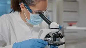 Diagnosis Prints: Biologist with face mask using microscope in science laboratory