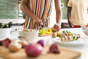 Culinary Prints: Biracial woman in a striped dress is chopping vegetables in a kitchen