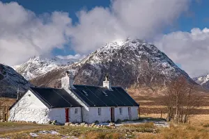 Hills Prints: Black Rock Cottage bothy on Rannoch Moor with a snow dusted Buachaille Etive Mor looming behind in winter
