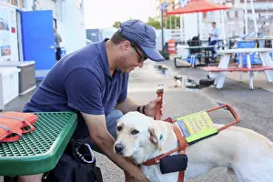 Mature Adult Prints: Blind man sitting with his service dog