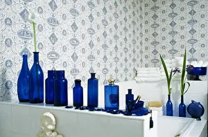 Details Prints: Blue and white wallpaper and collection of blue bottles on shelf above bath