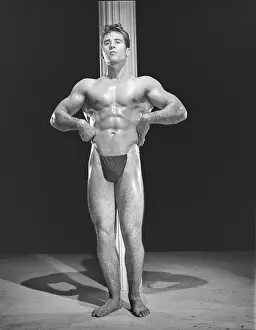 Bodybuilder Prints: Bodybuilder Poses In Front Of Pole c.1954