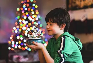 Snowman Prints: Boy holding Christmas decoration with tree lights in background