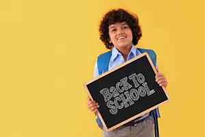 Expressive Prints: A BOY IN SCHOOL UNIFORM HAPPILY DISPLAYING MESSAGE OF BACK TO SCHOOL AFTER PANDEMIC